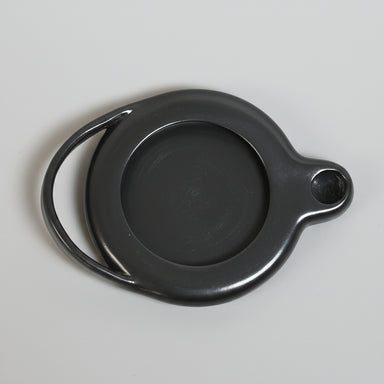 Black ceramic oil lamp on a beige background