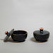 Two black ceramic containers (pyxis) with lids 
