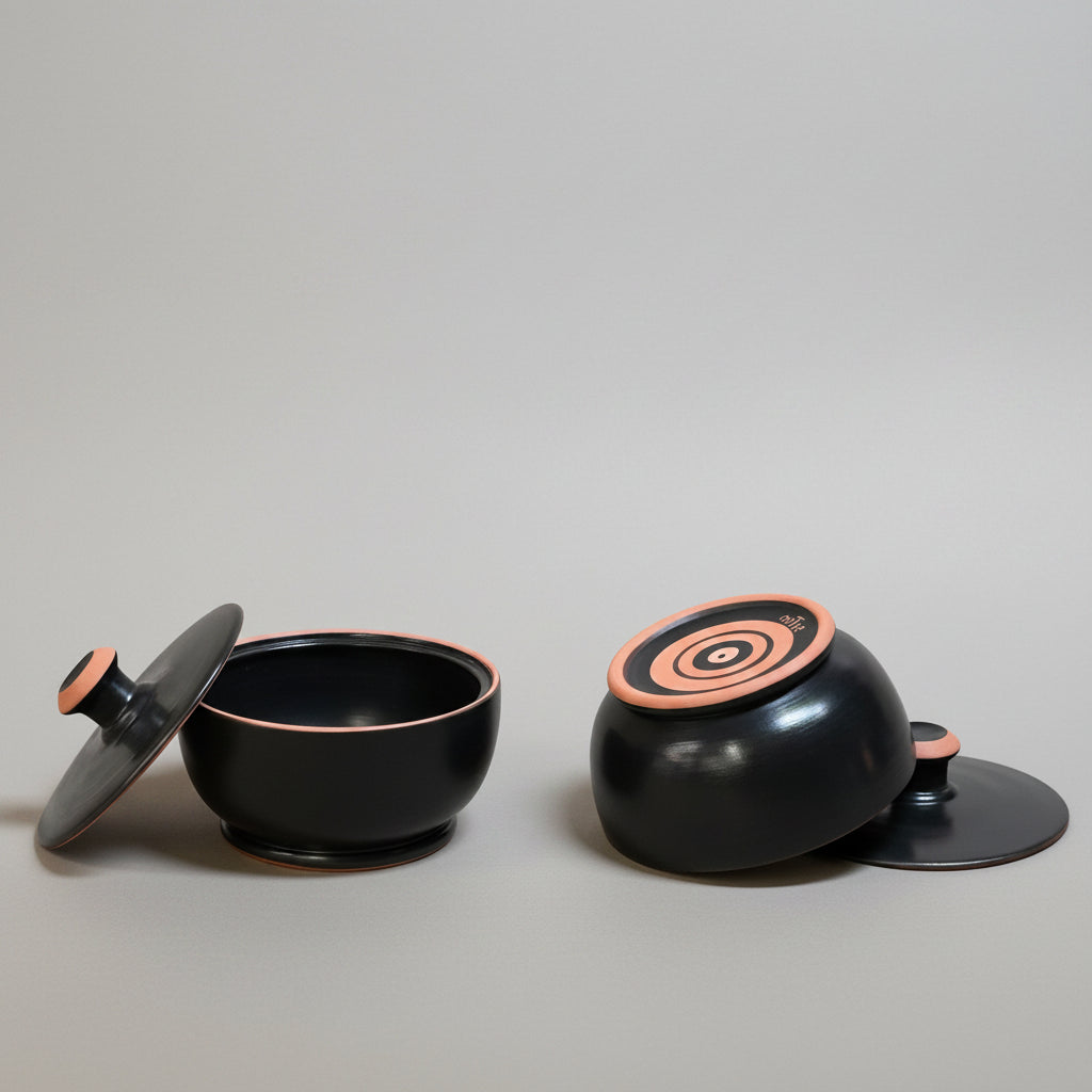Black and pinkish ceramic containers on a beige fabric background