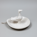 White ceramic dish with a duck-shaped object on a neutral background
