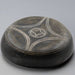 Black stone with white circular design on a gray background