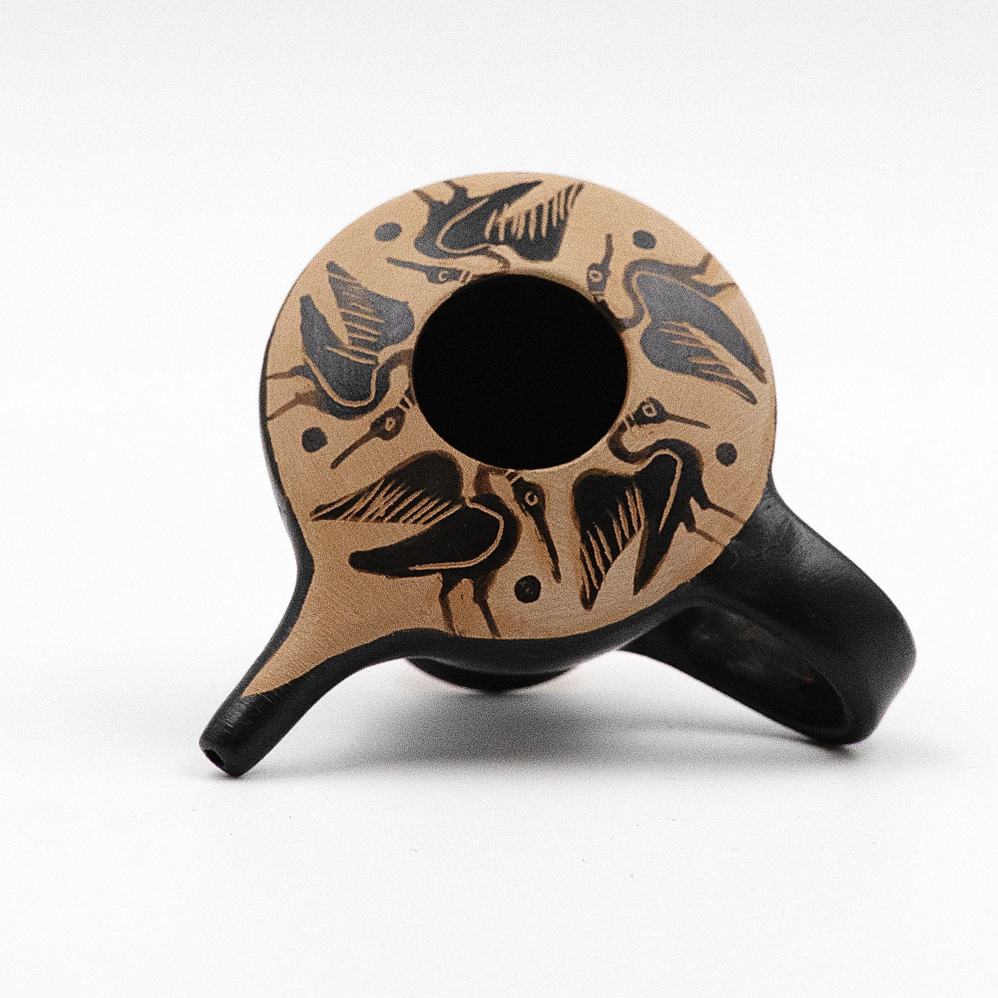 A small, black-figure ceramic vase with a handle, featuring elegant heron decorations around the rim.