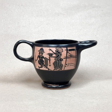 Black ceramic cup with pink decorative design on a beige background
