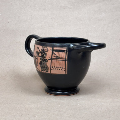 Black ceramic cup with pink and black design on a beige background