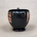 Black ceramic mug with pink geometric patterns on a beige background