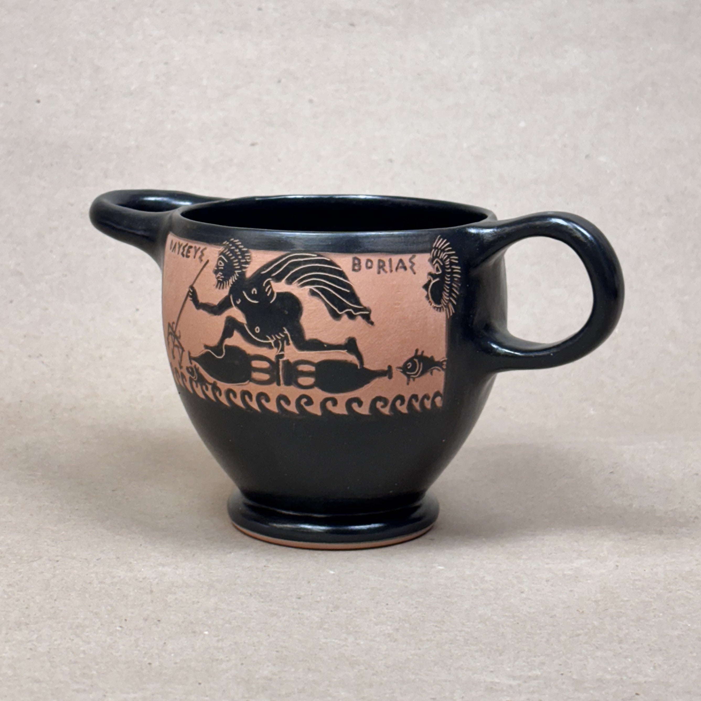 Black ceramic mug with decorative red and white pattern on a beige background