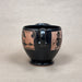 Black ceramic mug with decorative designs on a beige background