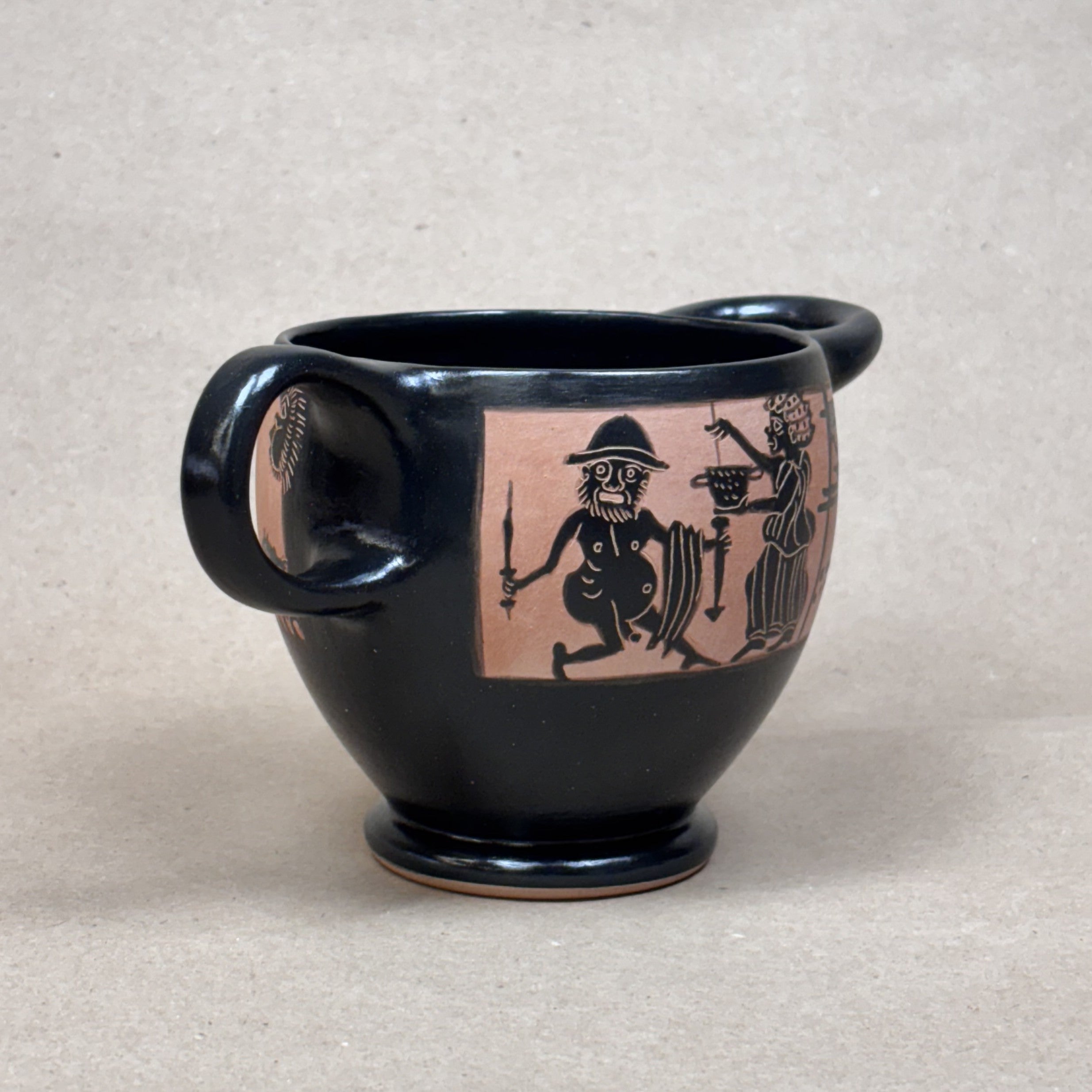 Black ceramic mug with ancient warrior design on a beige background