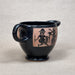 Black ceramic mug with ancient warrior design on a beige background