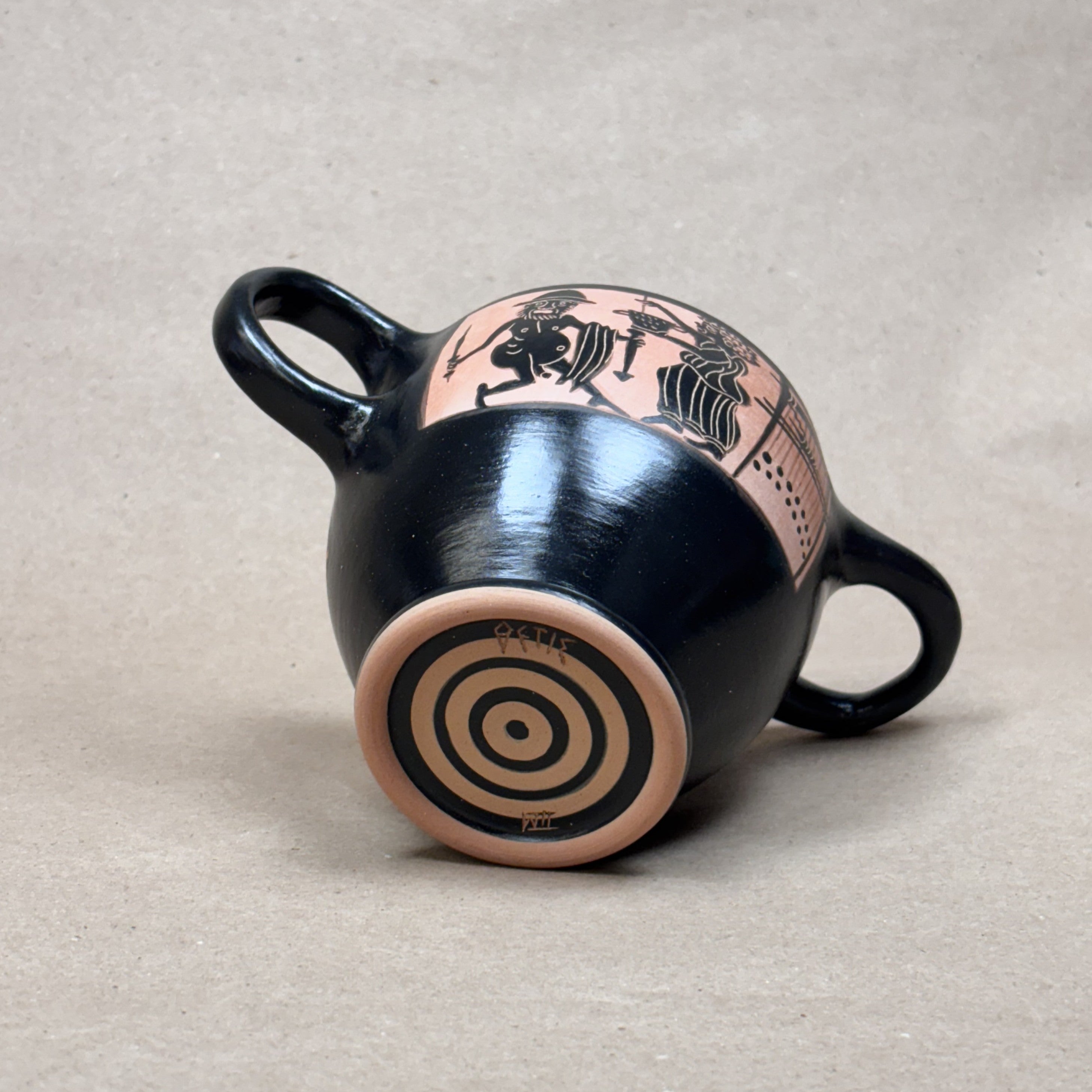 Black ceramic cup with pink and black designs on a beige background