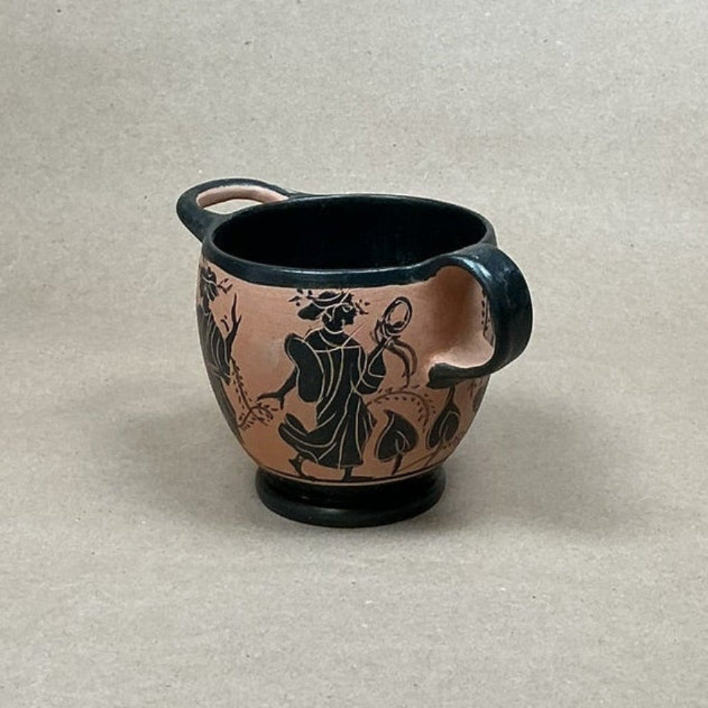 Ceramic cup with black handle and decorative design on a beige background