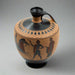 This image features a replica of an ancient Greek black-figure lekythos, a type of vase, dating back to the 6th century BCE. The lekythos is adorned with a detailed horse-racing scene, depicting athletes cheering on a youth and his galloping horse celebrating a victory in the games.