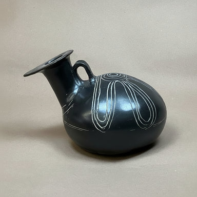 Black ceramic vase with white line design on a beige background