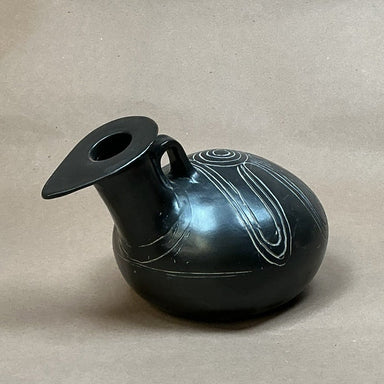 Black ceramic vase with decorative patterns on a beige background