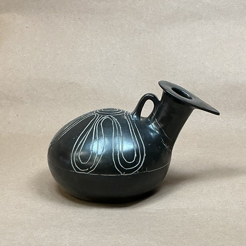 Black decorative vase on a beige surface 
