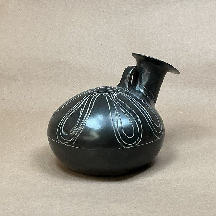 Black decorative vase on a beige surface 