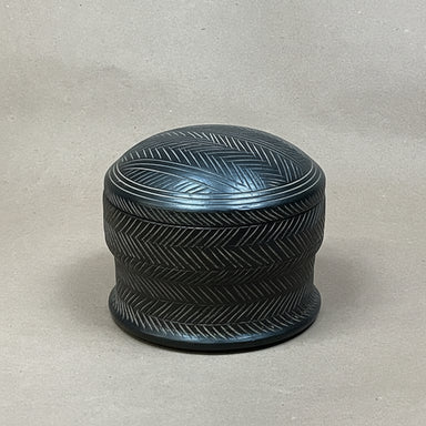 Black textured cylindrical container on a light gray background