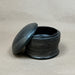 Black ceramic container with lid on a gray background