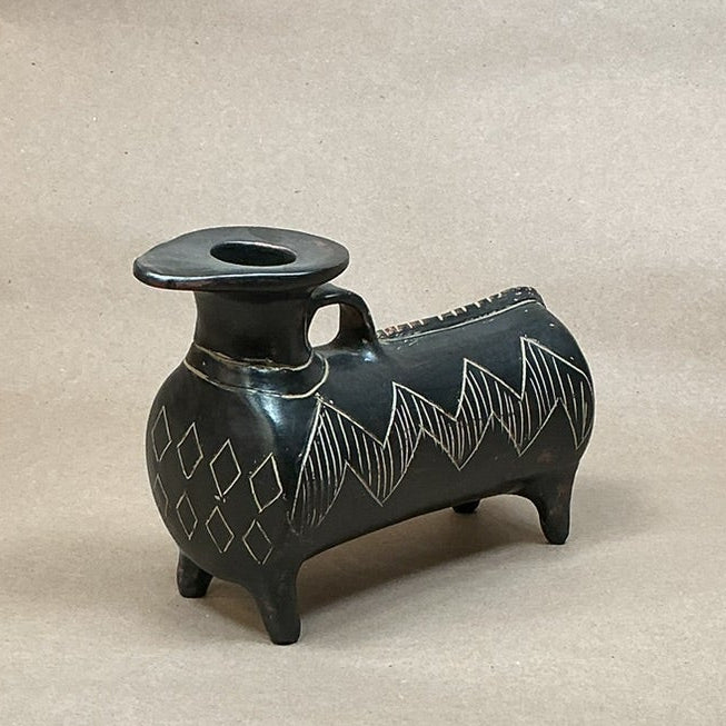 Small black decorative animal shaped vase on a light brown surface.