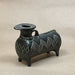 Small black decorative animal shaped vase on a light brown surface.
