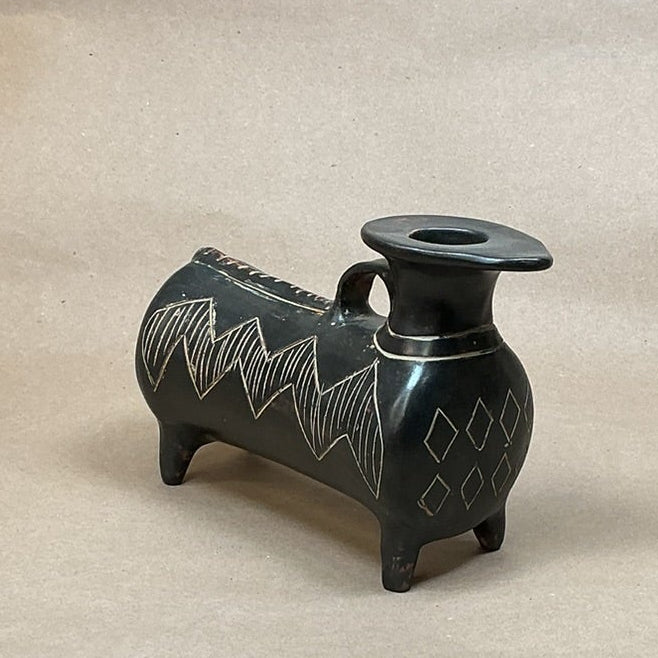 Small black decorative vase on a brown surface.