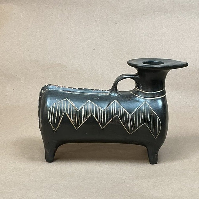 Black ceramic vase on a brown surface.