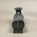 Small decorative vase on a wooden surface with a plain background