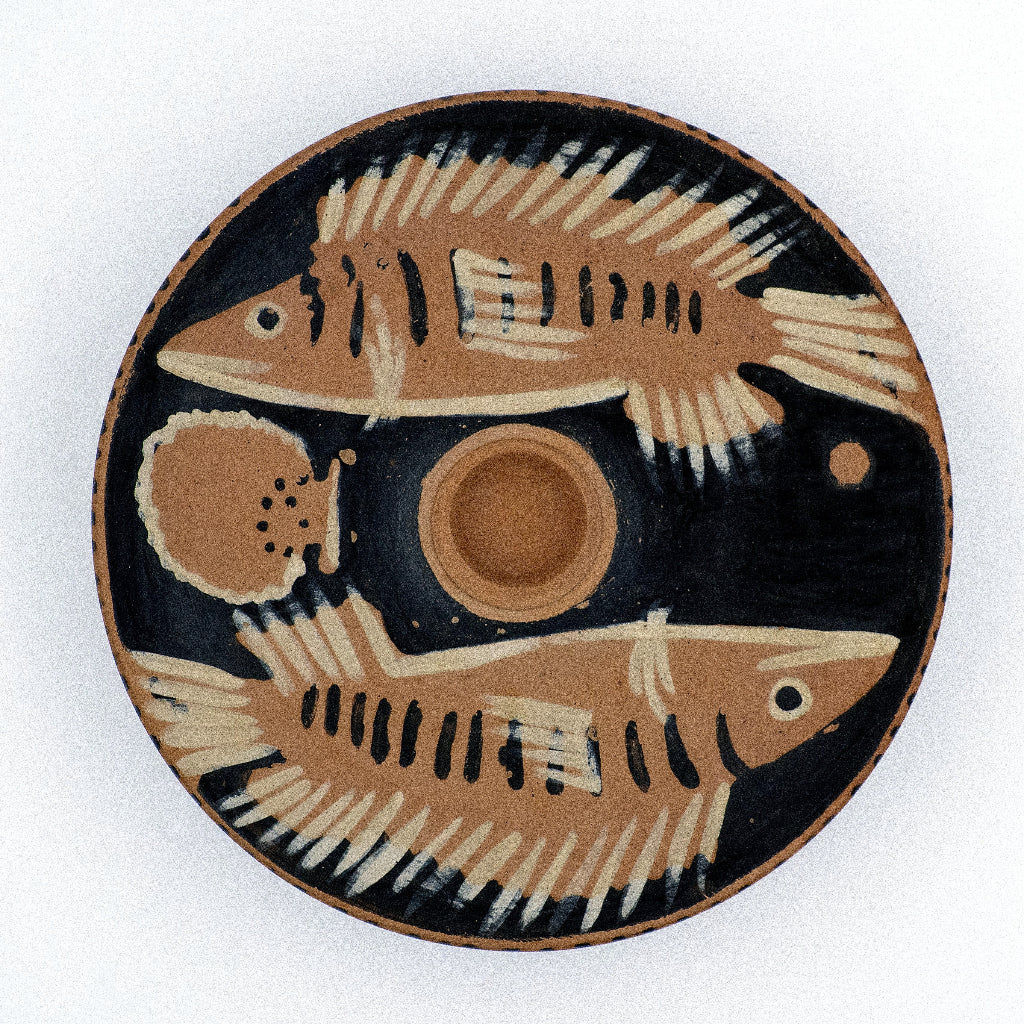 Red figure ceramic plate with fish design on a white background
