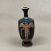Black vase with red decorative figure on a gray background