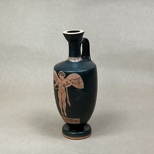 Black vase with brown decorative figure on a gray background