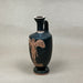 Black vase with brown decorative figure on a gray background