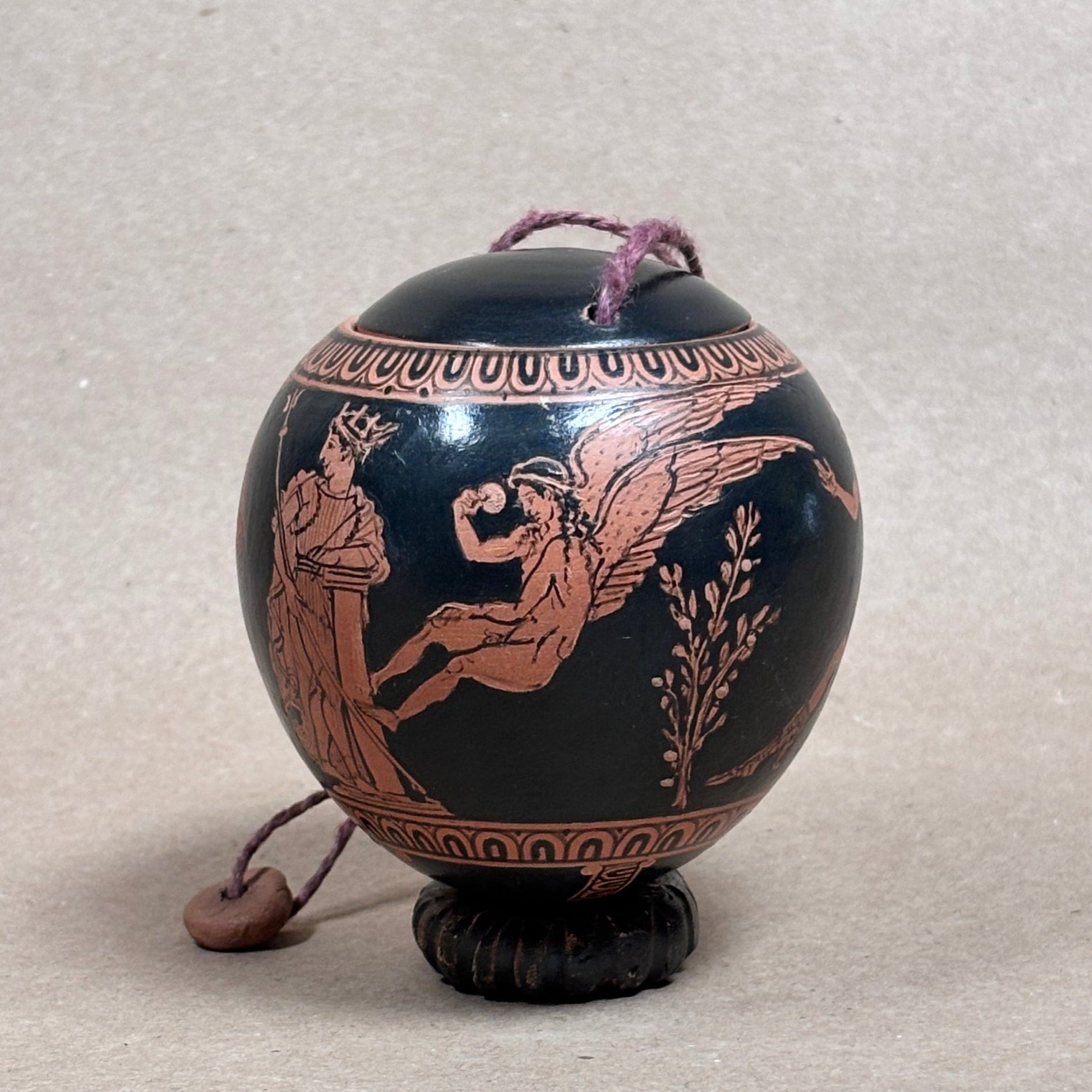 Decorative egg shaped ceramic box with classical design on a textured surface