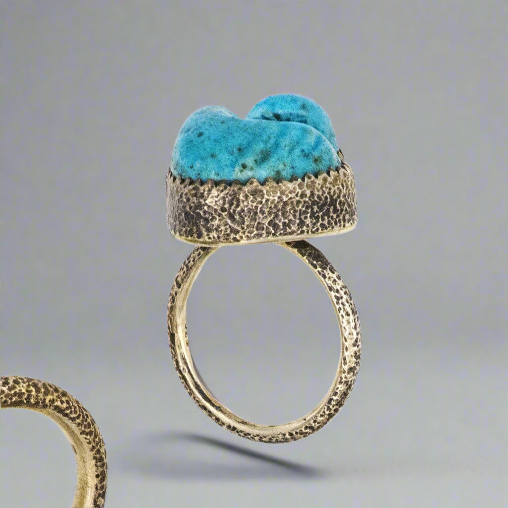 Gold ring with turquoise stone on a gray background