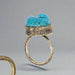 Gold ring with turquoise stone on a gray background