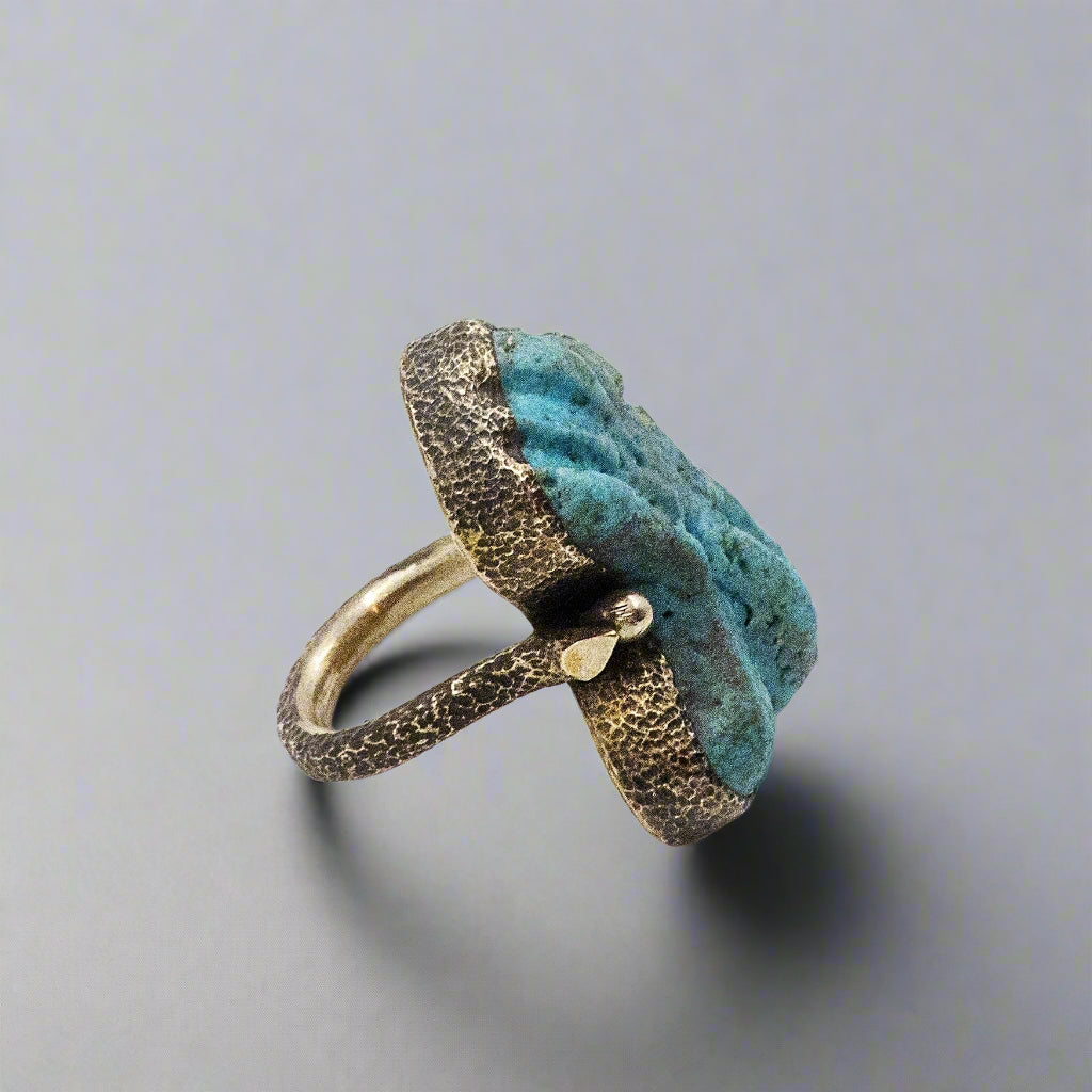 Ring with blue stone and bronze band on a white background