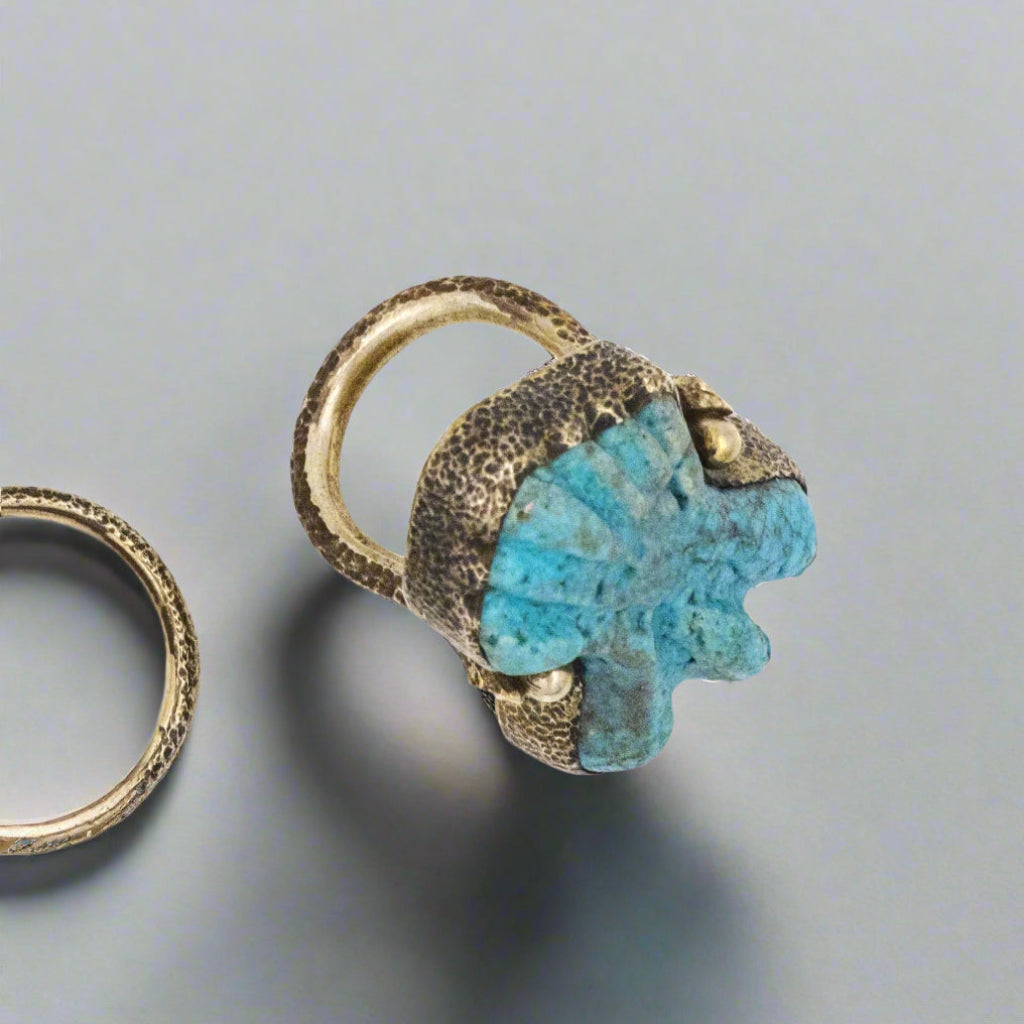 Ring with turquoise stone and gold accents on a white background