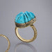 Ring with blue stone and textured gold band on a gray background