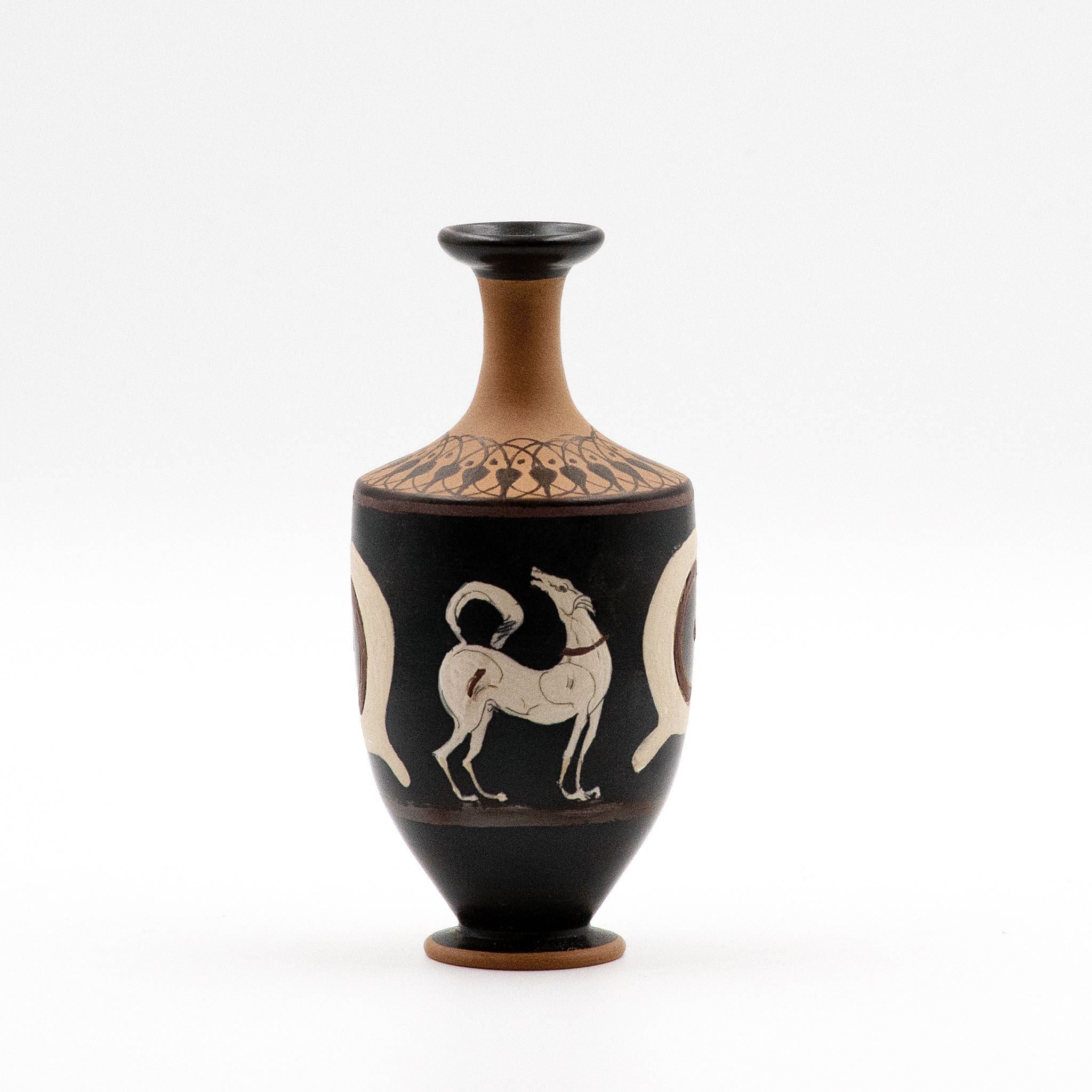 A small decorative vase with a black glossy surface featuring white and red floral patterns, including a howling dog and apotropaic eyes.