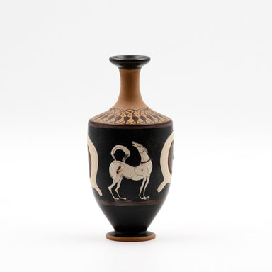 A small decorative vase with a black glossy surface featuring white and red floral patterns, including a howling dog and apotropaic eyes.