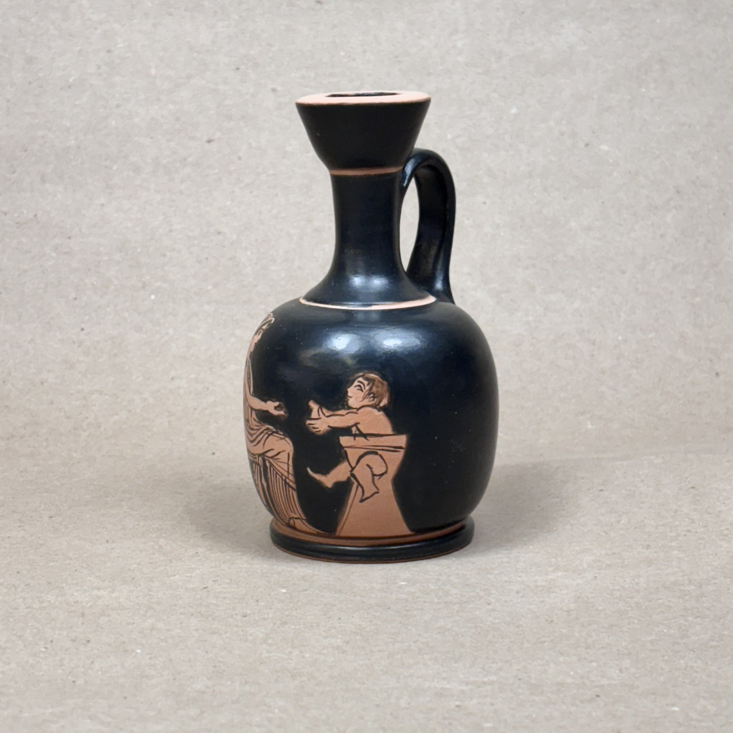 Black ceramic vase with red-figure decoration on a gray background