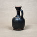 Black ceramic pitcher on a beige background