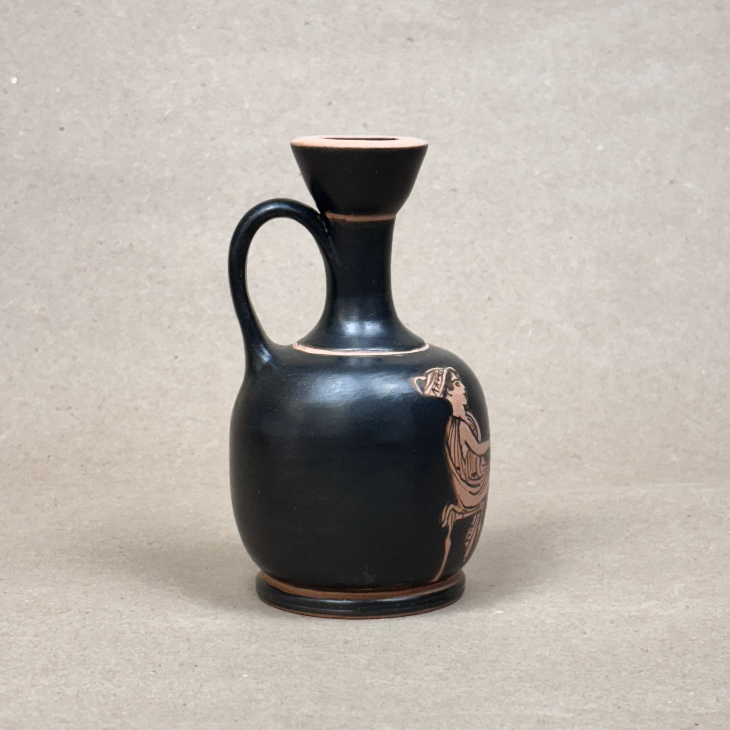 Black ceramic vase with decorative design on a beige background