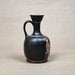Black ceramic vase with decorative design on a beige background