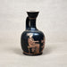 Black ceramic vase with red-figure decoration of a seated figure on a gray background