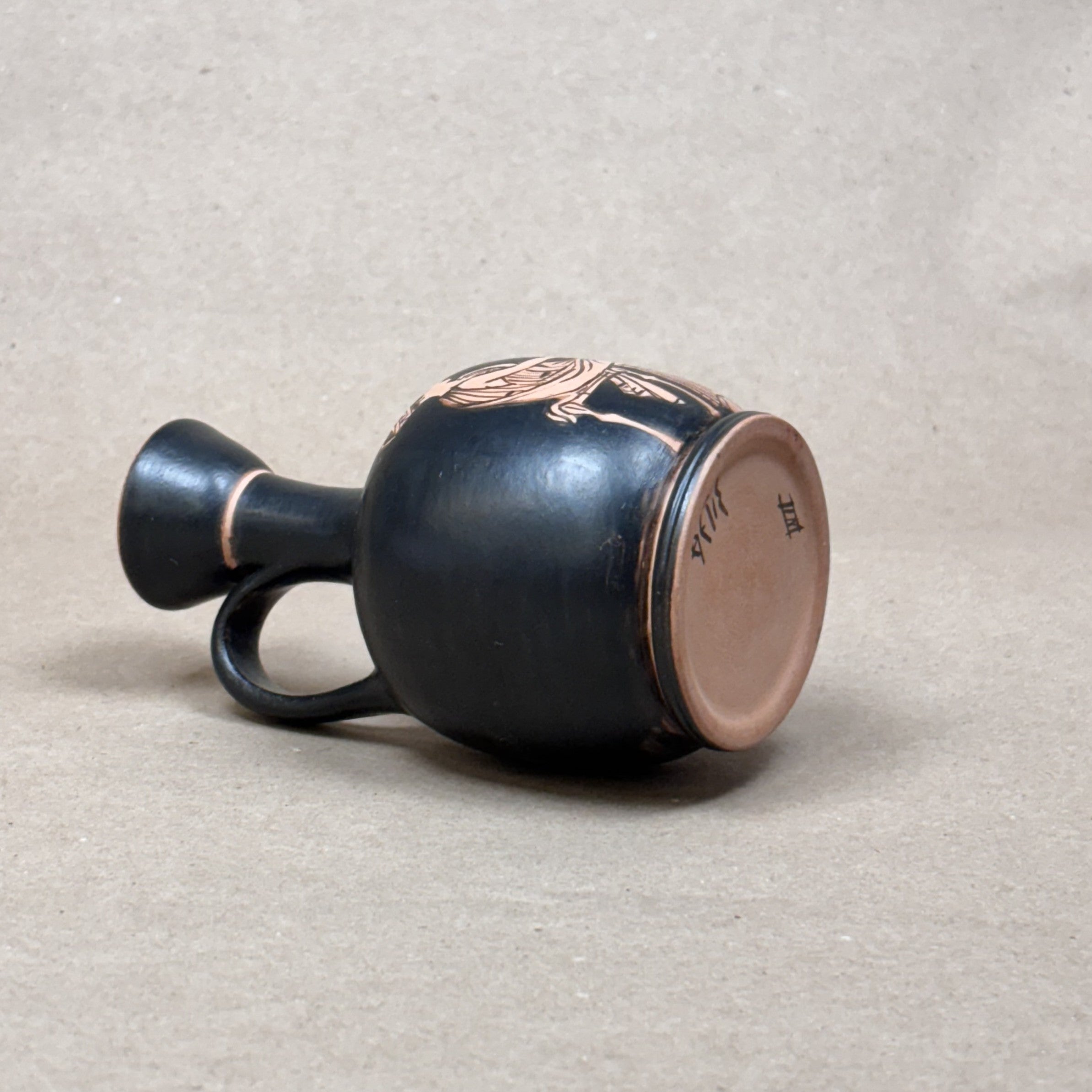 Black ceramic vase with decorative elements on a beige background