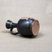 Black ceramic vase with decorative elements on a beige background