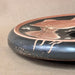 Ceramic plate with black background and red and white design on a beige surface