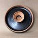 Ceramic bowl with a black interior and brown exterior on a beige background