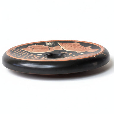 Ancient Greek black-figure plate with animal design on a white background