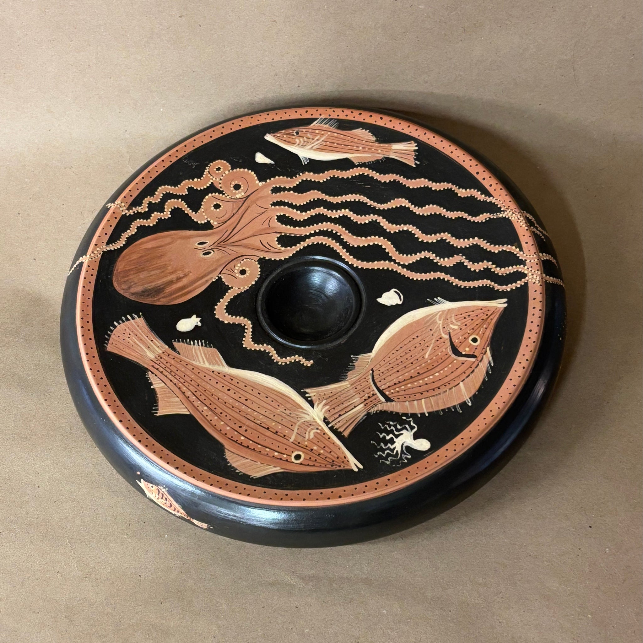 Decorative plate with fish and octopus design on a beige background